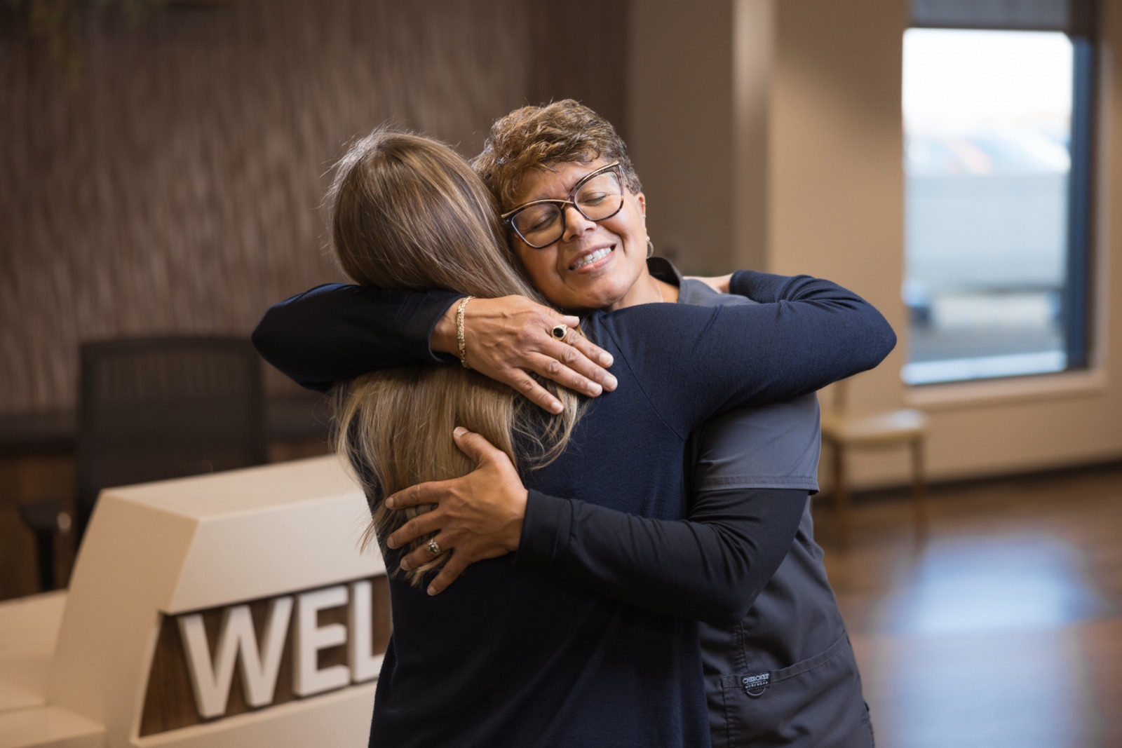 ADENA Health caregiver embracing a patient in a hospital lobby — healthcare marketing campaign still